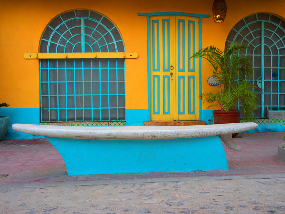 cute yellow and blue store with a surfboard bench