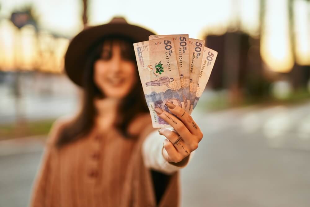 Woman in hat holding Colombian pesos