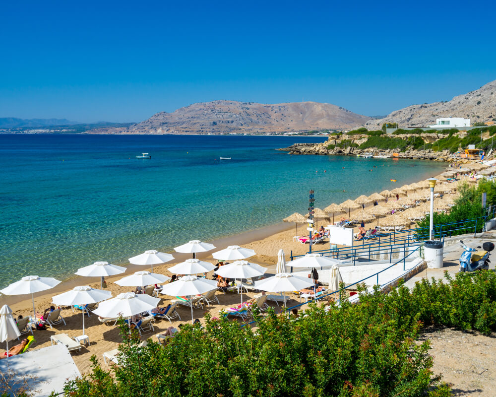 Rhodes has the best beaches, hills in the background and umbrellas for shade on the sand