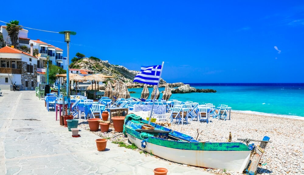 seaside tables and chairs and a boat in a Greek Island 