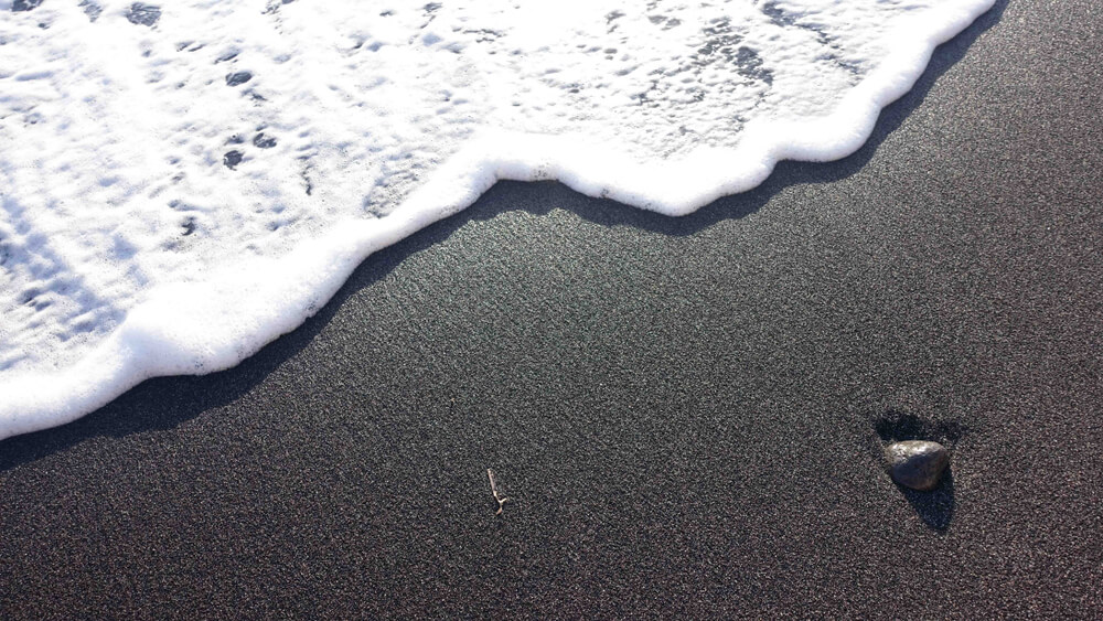 black sand with a white foamy wave