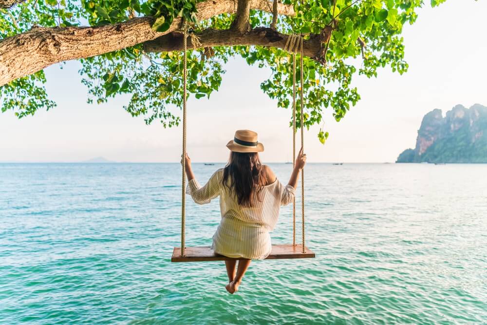 girl in swing over ocean in Thailand 