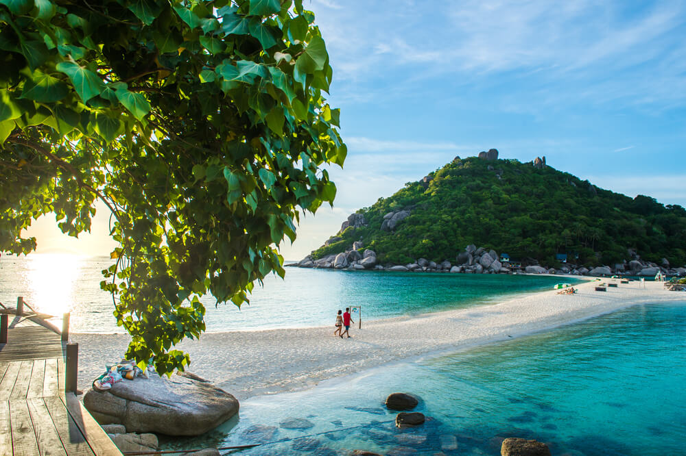 couple walking on a sandy spit of land in Thailand