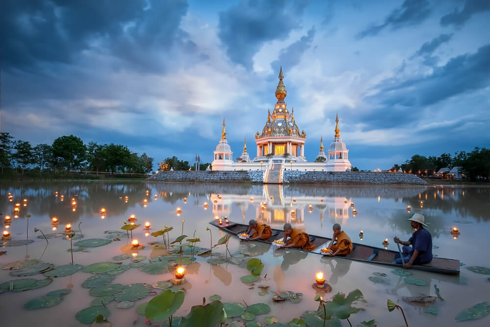 monks on boat in front of temple in Thailand