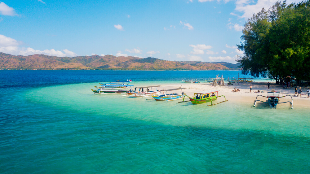 boats over clear water next to an island